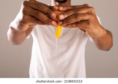 Midsection Of Man Breaking Egg Shell Against Gray Background. Unaltered, Food, Healthy Eating And Organic Concept.