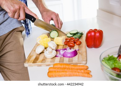 Mid-section of man chopping vegetable in kitchen at home