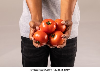 Midsection of man holding fresh red tomatoes standing against white background. unaltered, lifestyle, organic food and healthy eating concept.