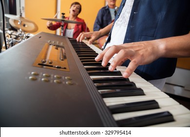 Midsection Of Man Playing Piano In Recording Studio