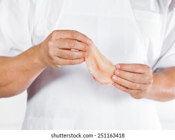 Midsection Of Mature Butcher Holding Chicken Meat In Shop