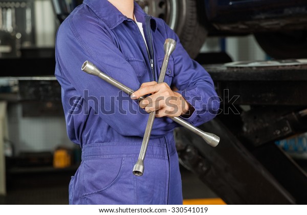Midsection of mechanic holding rim wrench in auto\
repair shop