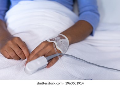 Midsection of mixed race female patient in hospital bed wearing fingertip pulse oximeter and iv tube. medicine, health and healthcare services. - Powered by Shutterstock