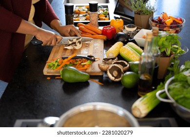 Midsection of plus size african american woman preparing dinner, chopping vegetables in kitchen. Healthy eating, cooking, body inclusivity and lifestyle, unaltered. - Powered by Shutterstock