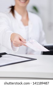 Midsection Of Receptionist Giving Check At Hospital Counter