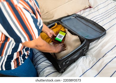 Midsection Of Senior African American Woman Packing Smartphone With Covid Vaccine Passport. Travel Preparation During Covid 19 Pandemic.