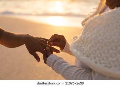 Midsection of senior biracial bride putting ring on bridegroom's finger at beach wedding ceremony. lifestyle, culture and love. - Powered by Shutterstock