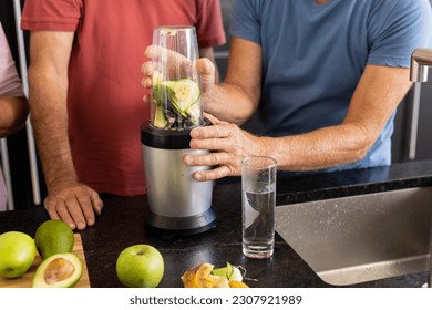 Midsection of senior caucasian male friends preparing healthy smoothies together in kitchen. Senior lifestyle, active retirement, nutrition, health and wellbeing, unaltered. - Powered by Shutterstock