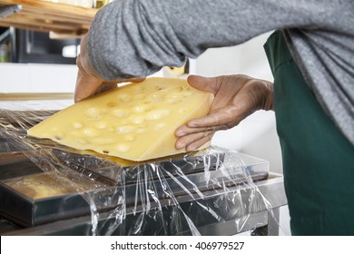 Midsection Of Senior Salesman Packing Cheese