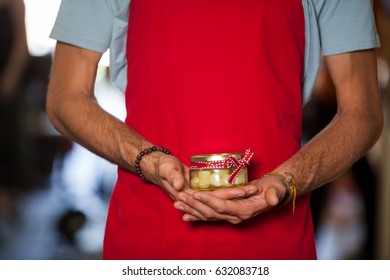 Mid-section of shop assistant holding a jar of pickle in grocery shop - Powered by Shutterstock