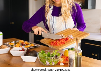 Midsection of smiling caucasian woman standing in kitchen preparing salad. Domestic life, food and healthy eating, spending time alone at home. - Powered by Shutterstock