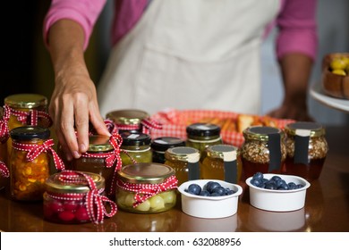 Mid-section of staff arranging jar at counter in market - Powered by Shutterstock