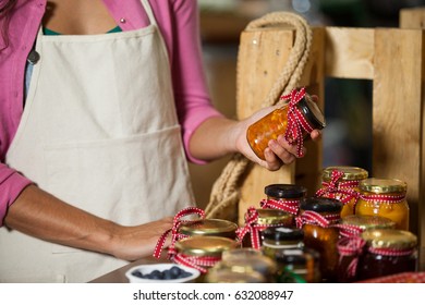 Mid-section of staff checking pickle jar at counter in market - Powered by Shutterstock