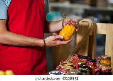 Mid-section of staff checking pickle jar at counter in market - Powered by Shutterstock