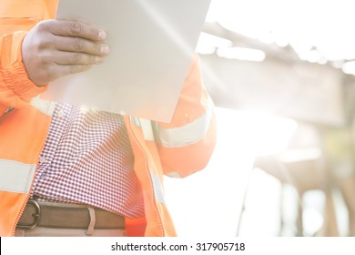 Midsection Supervisor Holding Clipboard At Construction Site On Sunny Day