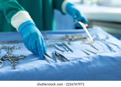 Midsection of surgical tech placing surgical tools on table in operating theatre. Hospital, medical and healthcare services. - Powered by Shutterstock