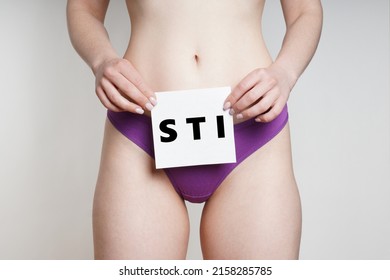 Midsection Of Unrecognizable Woman In Panties Holding Woman In Panties Holding Sign Wit STI For Sexually Transmiited Infection Or Disease