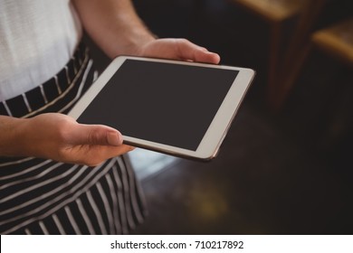 Midsection Of Waiter Holding Digital Tablet At Cafe