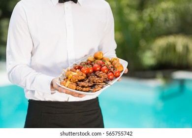 Midsection Of Waiter Holding Food Tray At Poolside