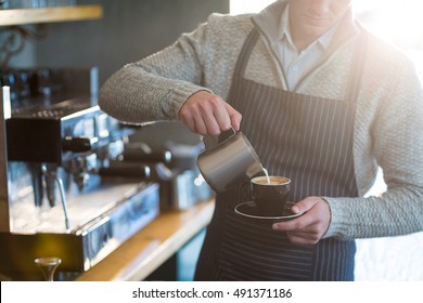 Mittelteil des Kellners, der eine Tasse Kaffee an der Theke im Café kocht – Stockfoto