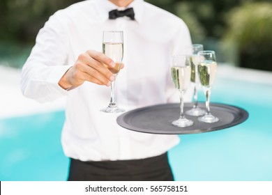 Midsection Of Waiter Offering Champagne At Poolside