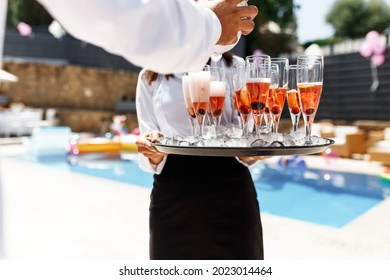 Midsection Of Waiter Pouring Champagne At Poolside.Serving With Ice On A Tray. Swimming Pool Party Concept.