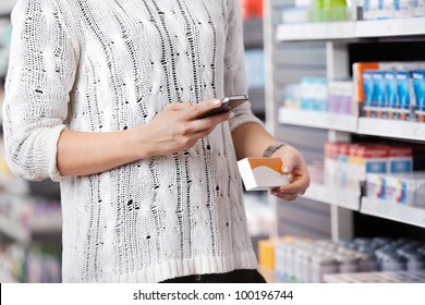 Mid-section Of Woman Holding Medication Box And Dialing On Cell Phone