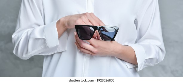 Midsection Of Woman Holding Sunglasses. Background For Product Display, Banner, Or Mockup
