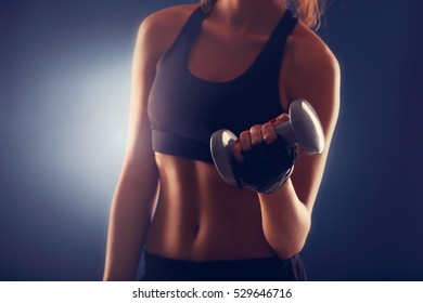 Midsection Of Woman Lifting Dumbells