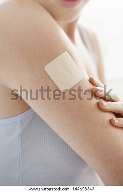 Midsection woman with nicotine patch on arm\
over white\
background