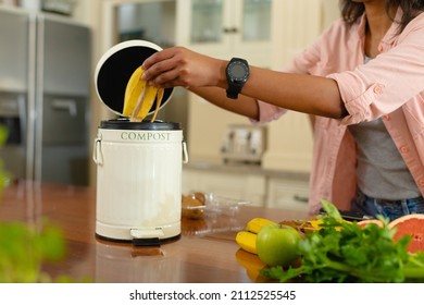 Midsection of young african american woman putting banana peel in compost bin at home. people and compost technology concept, unaltered. - Powered by Shutterstock