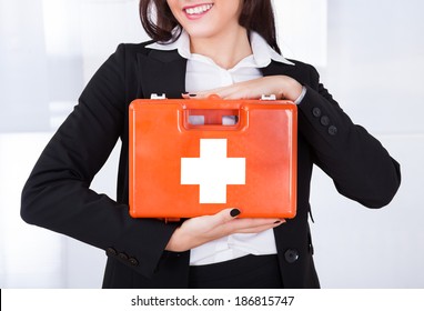 Midsection Of Young Businesswoman Holding First Aid Box In Office