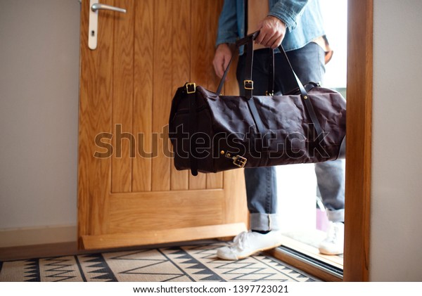 Midsection of young man with bag entering front\
door when coming back\
home.