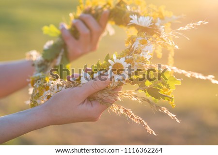 Midsummer in Latvia: celebration of Ligo - a young woman weave a wreath and collect field flowers