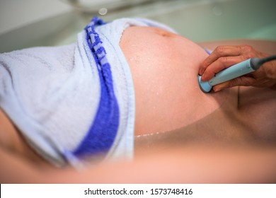 Midwife Checks The Heart Beat Of A Child. Natural Birth In Water.