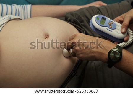 Midwife listening to the heartbeats of an unborn