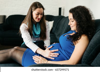 Midwife making home visit to a pregnant woman and checking her belly