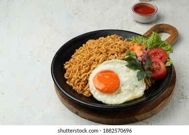 Mie goreng or Fried noodles served with eggs and vegetables, on a plate - Shutterstock ID 1882570696