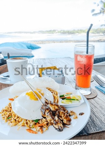 Mie goreng (fried noodles) served with two sticks of chicken satay and a fried egg at a restaurant on the Medewi Beach in Bali, Indonesia.