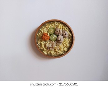 mie kocok. traditional food from Bandung, Indonesia. savory taste. consist of noodle, meat ball, cow gravel, lime and hot chili. served on wooden bowl. isolated background in white.