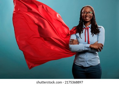 Mighty Looking Tough Superhero Woman Wearing Red Hero Costume Cape Standing With Arms Crossed On Blue Background. Portrait Of Young Adult Person Posing As Justice Defender While Smiling At Camera.