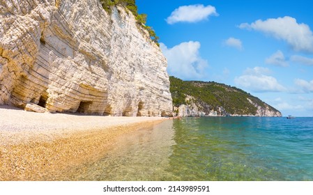 Mighty and white rock walls protecting famous Baia delle Zagare (Zagare Bay) or Baia dei Mergoli (Mergoli Bay) with Faraglioni di Puglia, Gargano National Park, Puglia, Italy - Shutterstock ID 2143989591