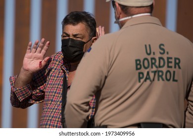 A migrant from Columbia shows his injured hand to a Border Patrol agent after turning himself over to authorities on May 13, 2021 in Yuma, Arizona.