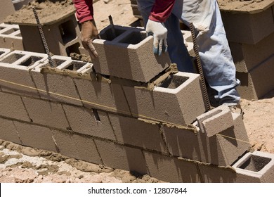 Migrant Worker Building Cinder Block Wall In Desert Setting.