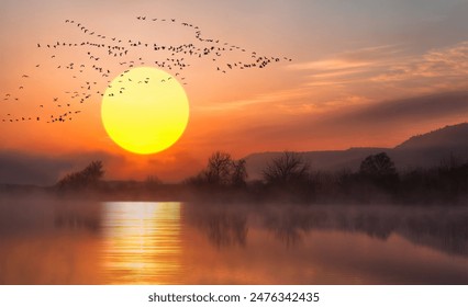 A migrating flock of geese flying in V-formation across a lake at sunset sky. - Powered by Shutterstock