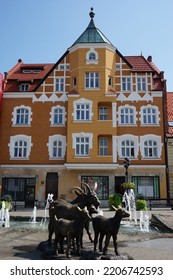 Mikolow, Poland - August 27 2022: Facade Of Tenement House Is Asymmetrically Divided By Stone Bay Window. Building Comes From Beginning Of  19th Century. Sculpture Group In Front Of The Building.