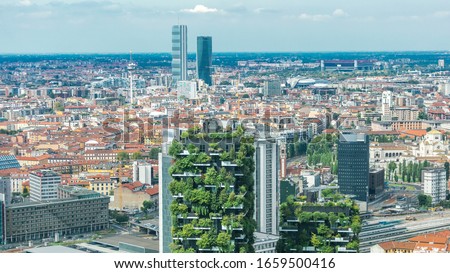 Milan aerial view of modern towers and skyscrapers and the Garibaldi railway station in the business district timelapse fiew from rooftop. Houses with red roofs. Blue cloudy sky at summer day