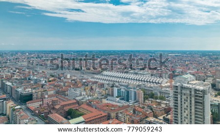 Milan aerial view of residential buildings and the central railway station in the business district timelapse fiew from rooftop. Houses with red roofs. Blue cloudy sky at summer day