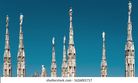 Milan Cathedral roof, Italy. Famous Milan Cathedral or Duomo di Milano is a top landmark of Milan. Many luxury spires with statues on blue sky background. Beautiful Gothic architecture of Milan city.