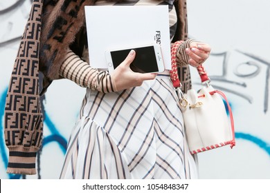 MILAN - FEBRUARY 22: Woman with Fendi brown fur jacket with bag and smartphone in hand before Fendi fashion show, Milan Fashion Week street style on February 22, 2018 in Milan.